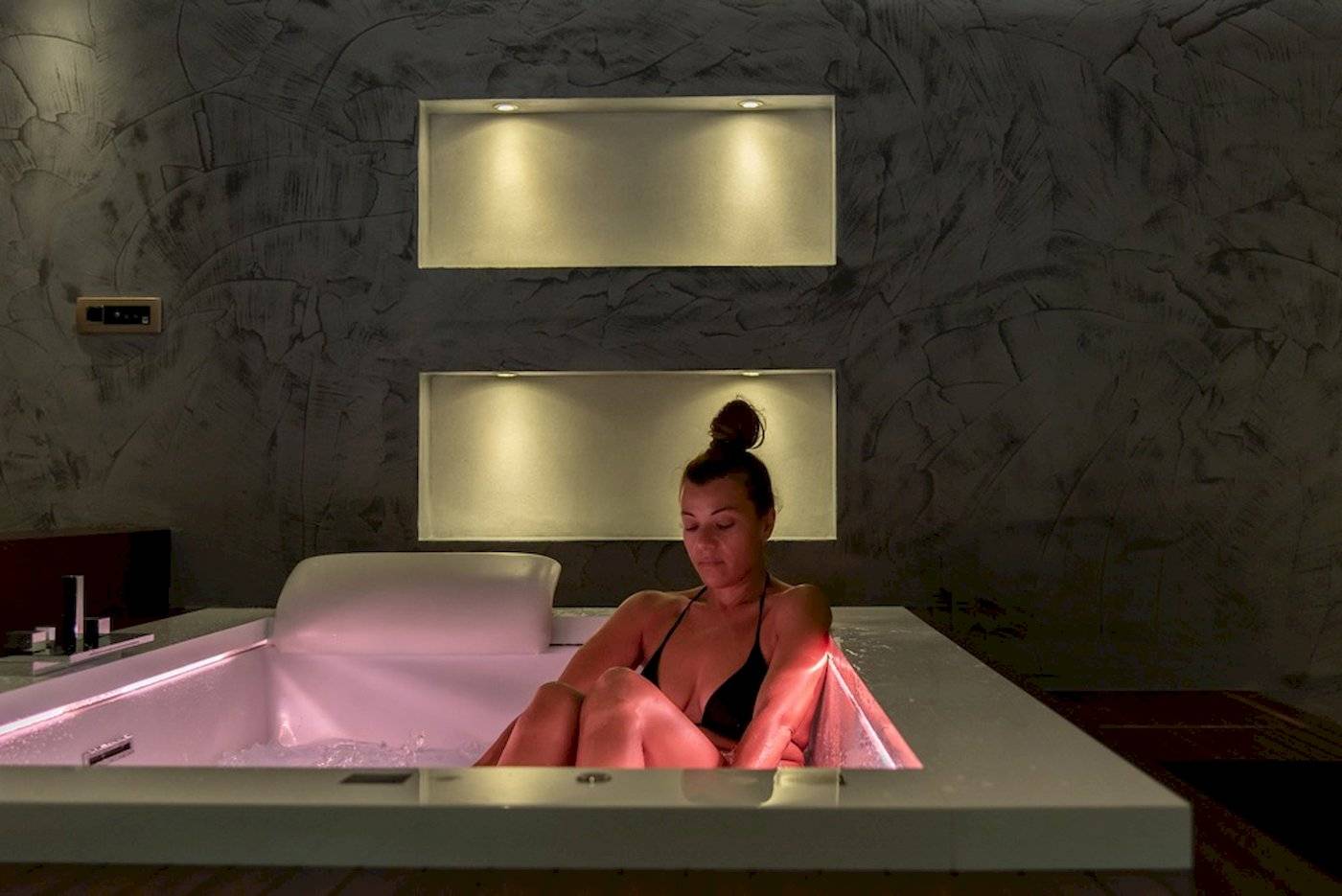 Frau in pink beleuchteter Badewanne