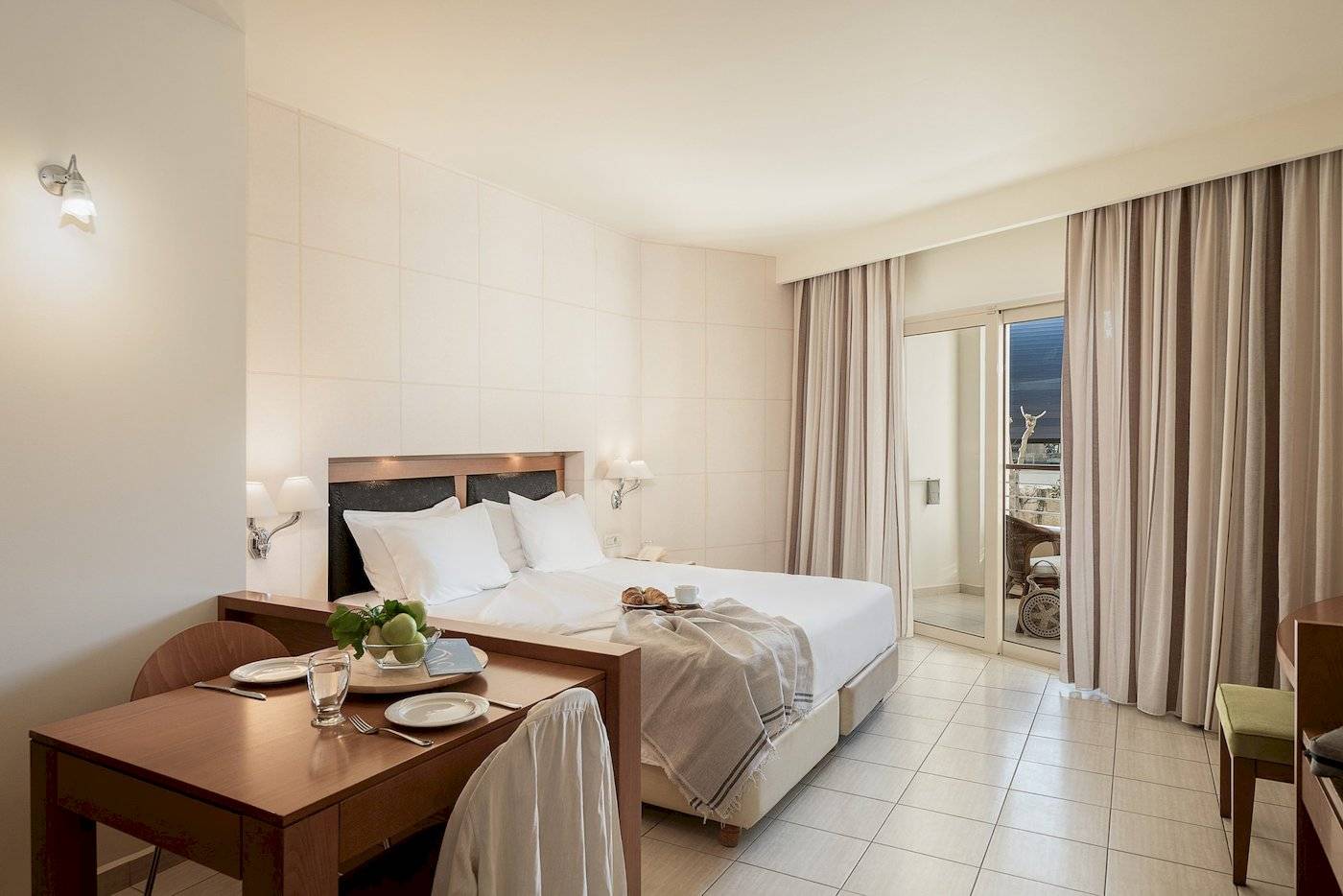 Innenansicht eines Zimmers im Cretan Dream Resort & Spa Hotel mit einem Bett, Tisch und Balkon