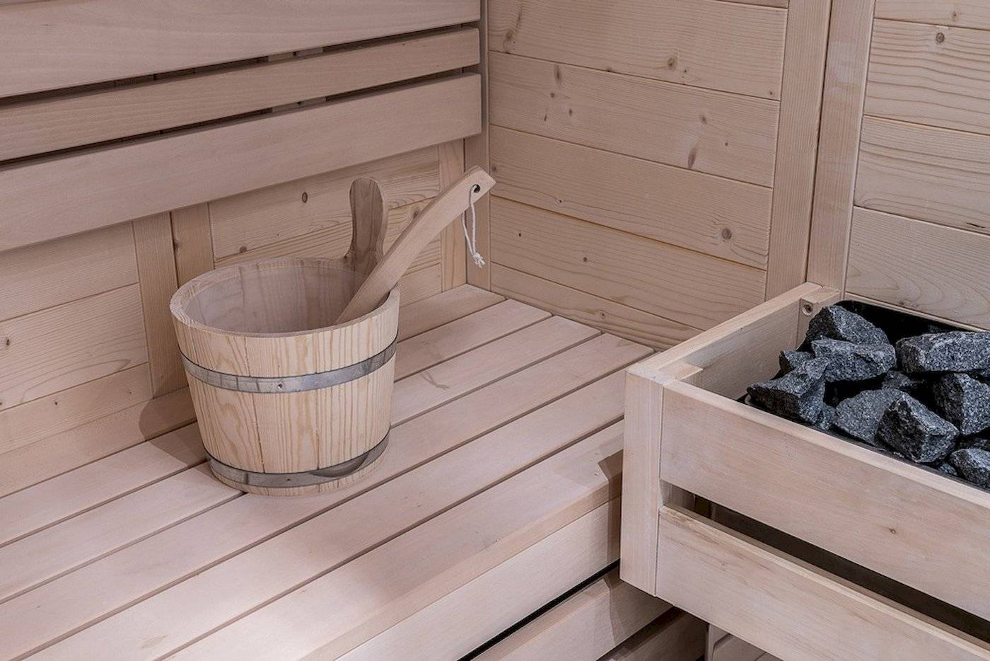 Innenraum einer Holzsauna mit einem Eimer und Steinen