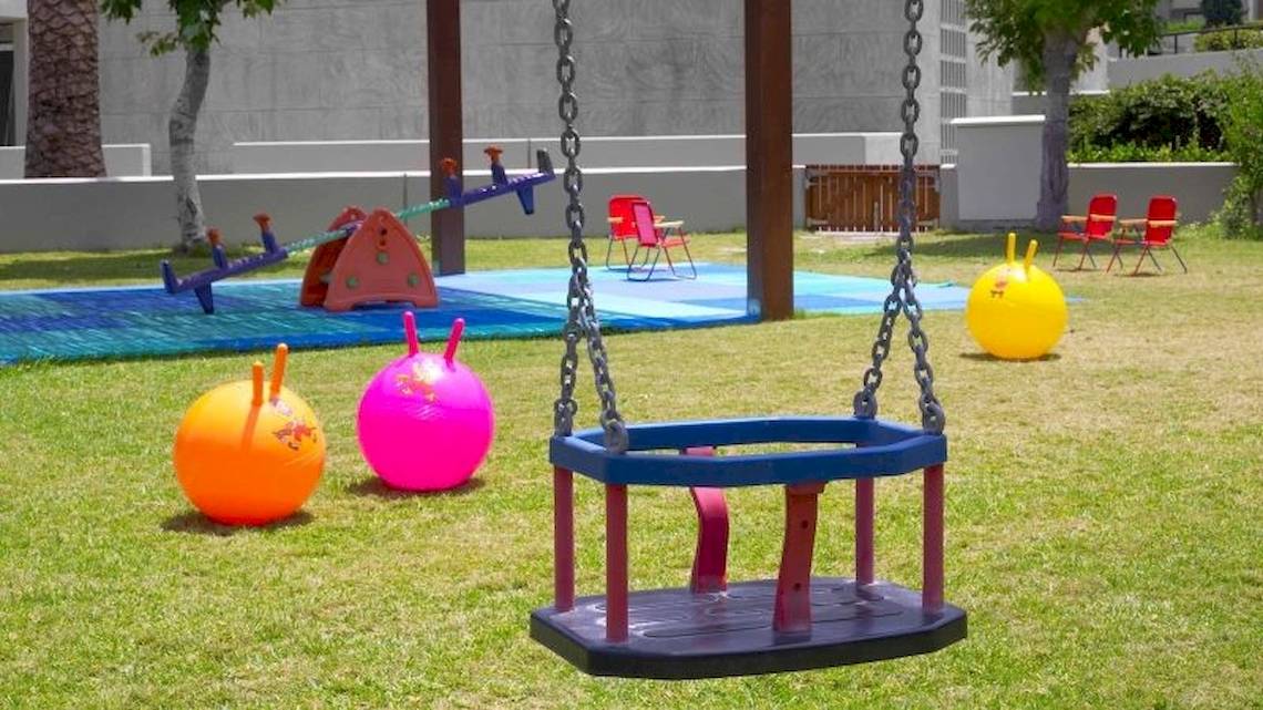Kinderspielplatz im Sheraton Rhodes Resort mit Schaukel, bunten Bällen und Spielgeräten.