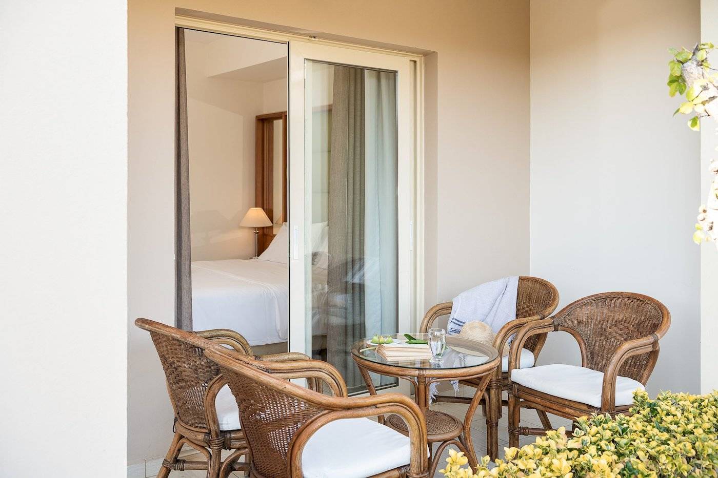 Ein Balkonbereich mit einem Tisch, Stühlen und einem Bett im Hintergrund im Cretan Dream Resort & Spa.