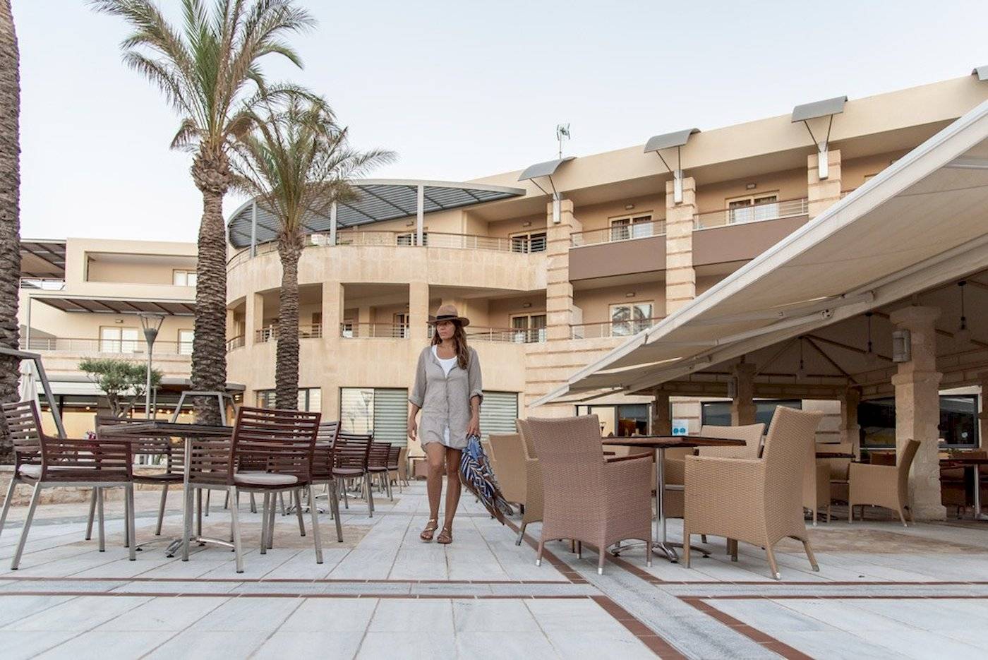 Frau im Sommerkleid und Hut geht vor dem Cretan Dream Resort & Spa entlang
