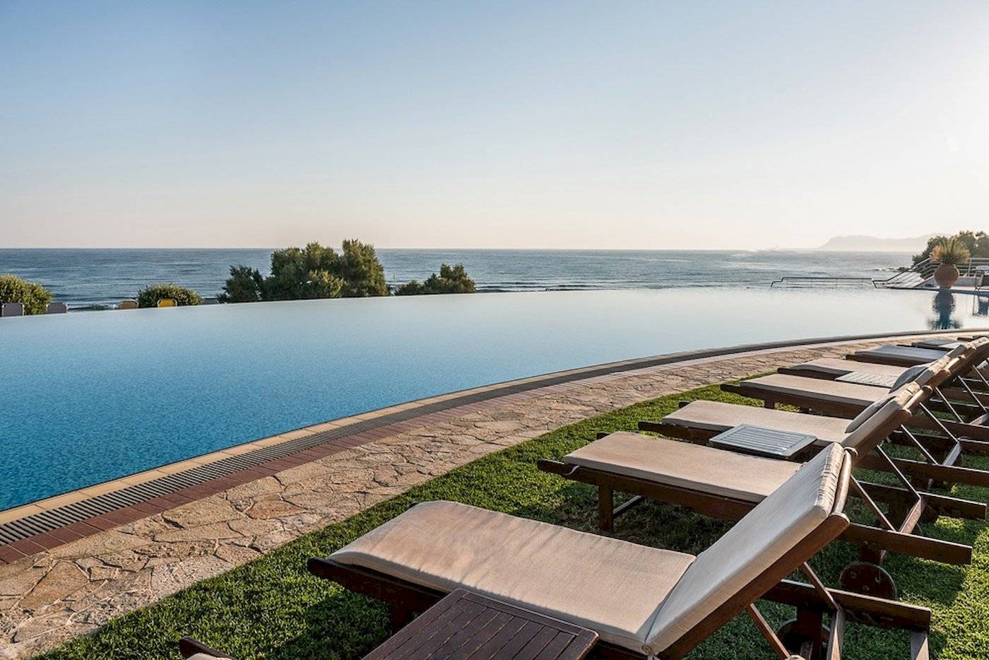 Außenpool mit Sonnenliegen am Cretan Dream Resort & Spa mit Blick auf das Meer.