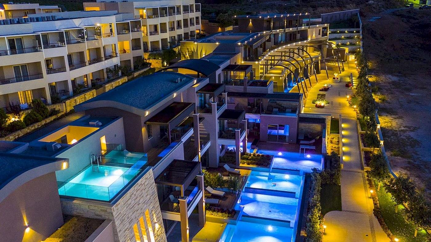 Luftaufnahme des Cretan Dream Resort & Spa bei Nacht mit beleuchteten Gebäuden und Swimmingpools.