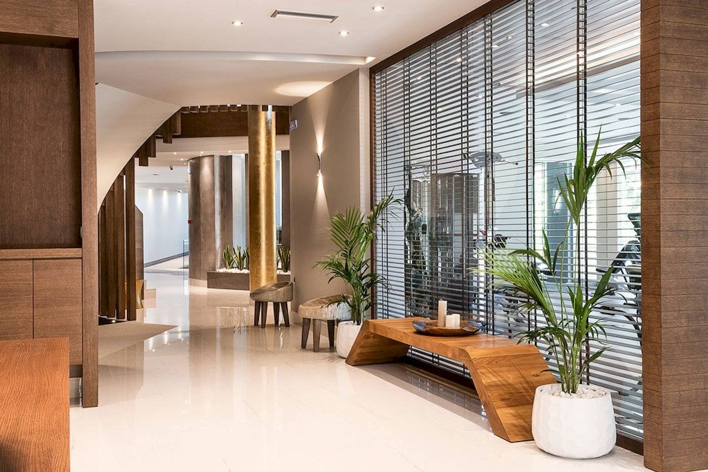 Innenbereich des Cretan Dream Resort & Spa mit Holzmöbeln, Pflanzen und einer Wendeltreppe.