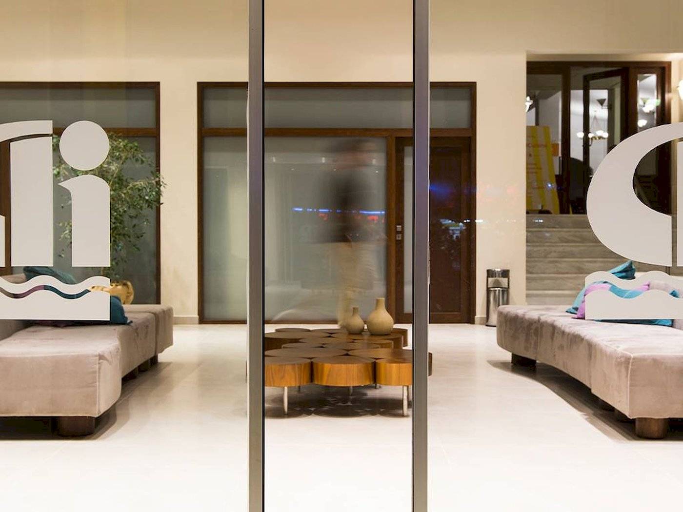 Lobby des Chrissi Amoudia Hotels mit modernen Möbeln und einem zentralen Tisch.