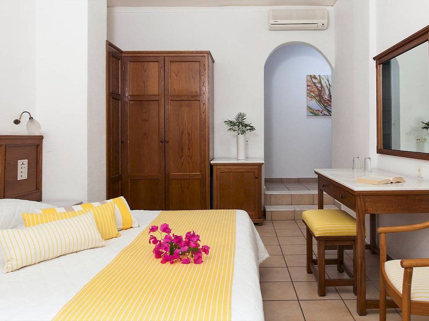 Innenansicht eines Zimmers im Chrissi Amoudia Hotel mit Bett, Dekor und Möbeln.