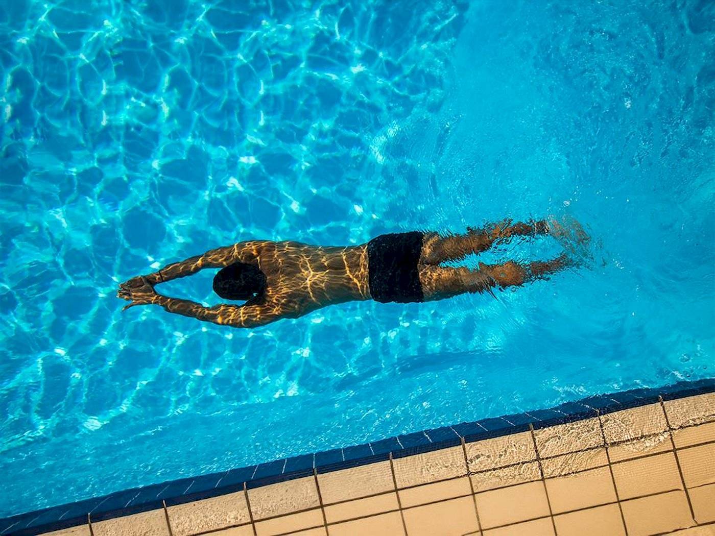 Ein Mann schwimmt im Pool von Chrissi Amoudia Hotel.