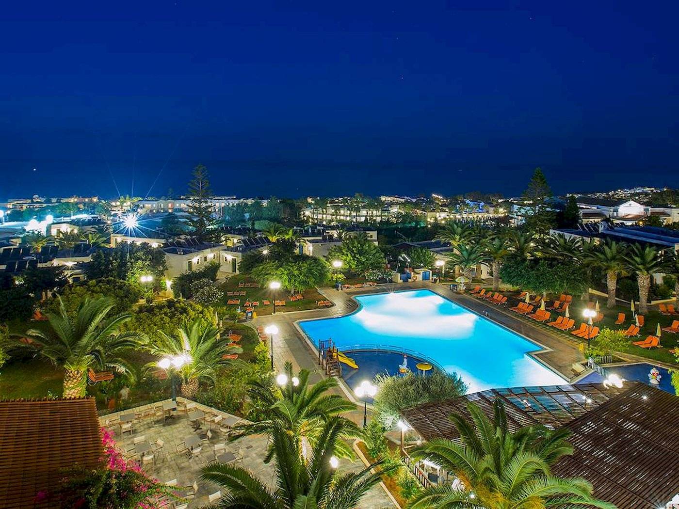 Abendliche Ansicht des Chrissi Amoudia Hotels mit Swimmingpool und Sonnenliegen