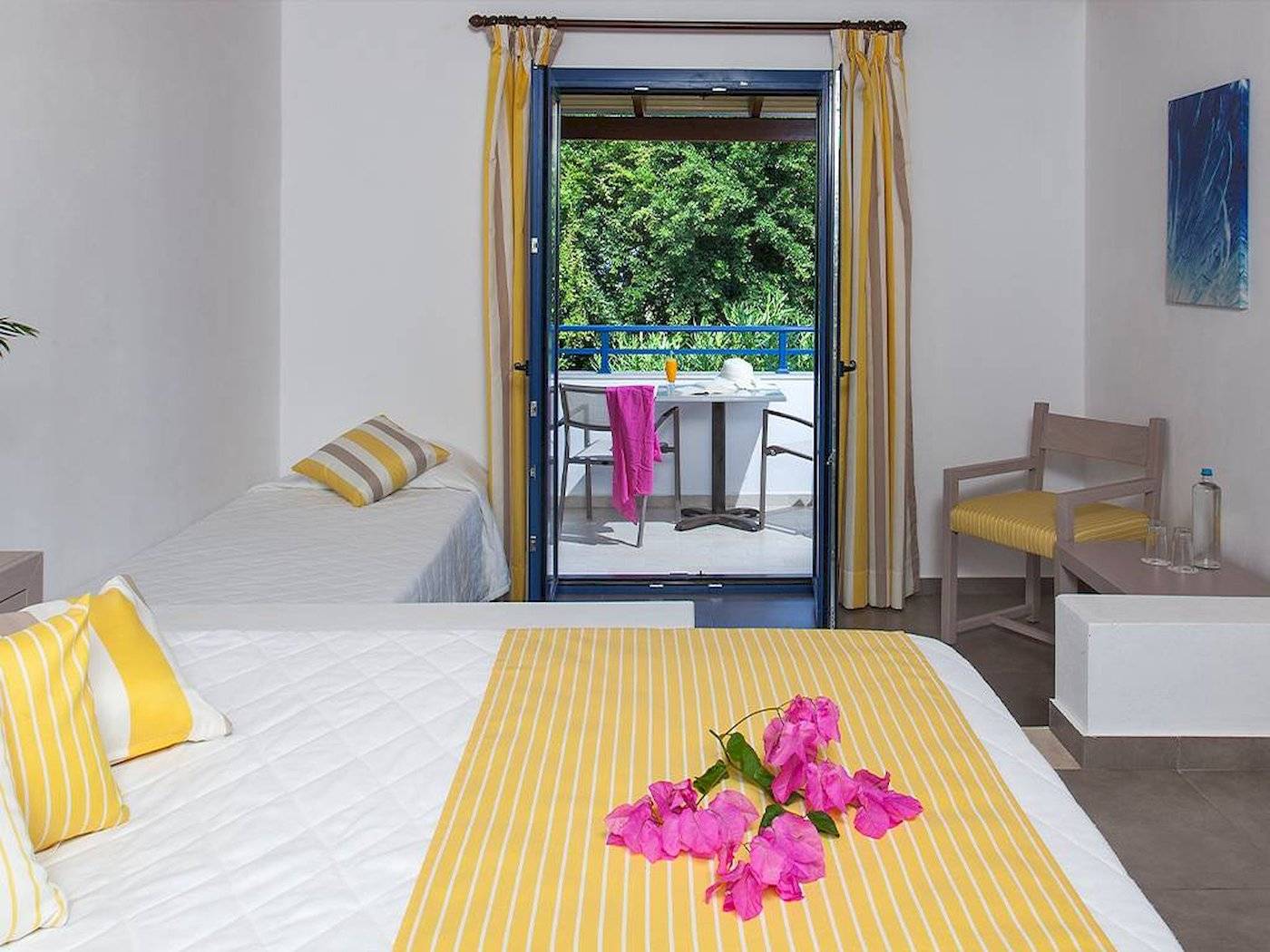 Doppelzimmer mit Balkon im Hotel Chrissi Amoudia mit Blick auf eine Terrasse mit Tisch und Stühlen.