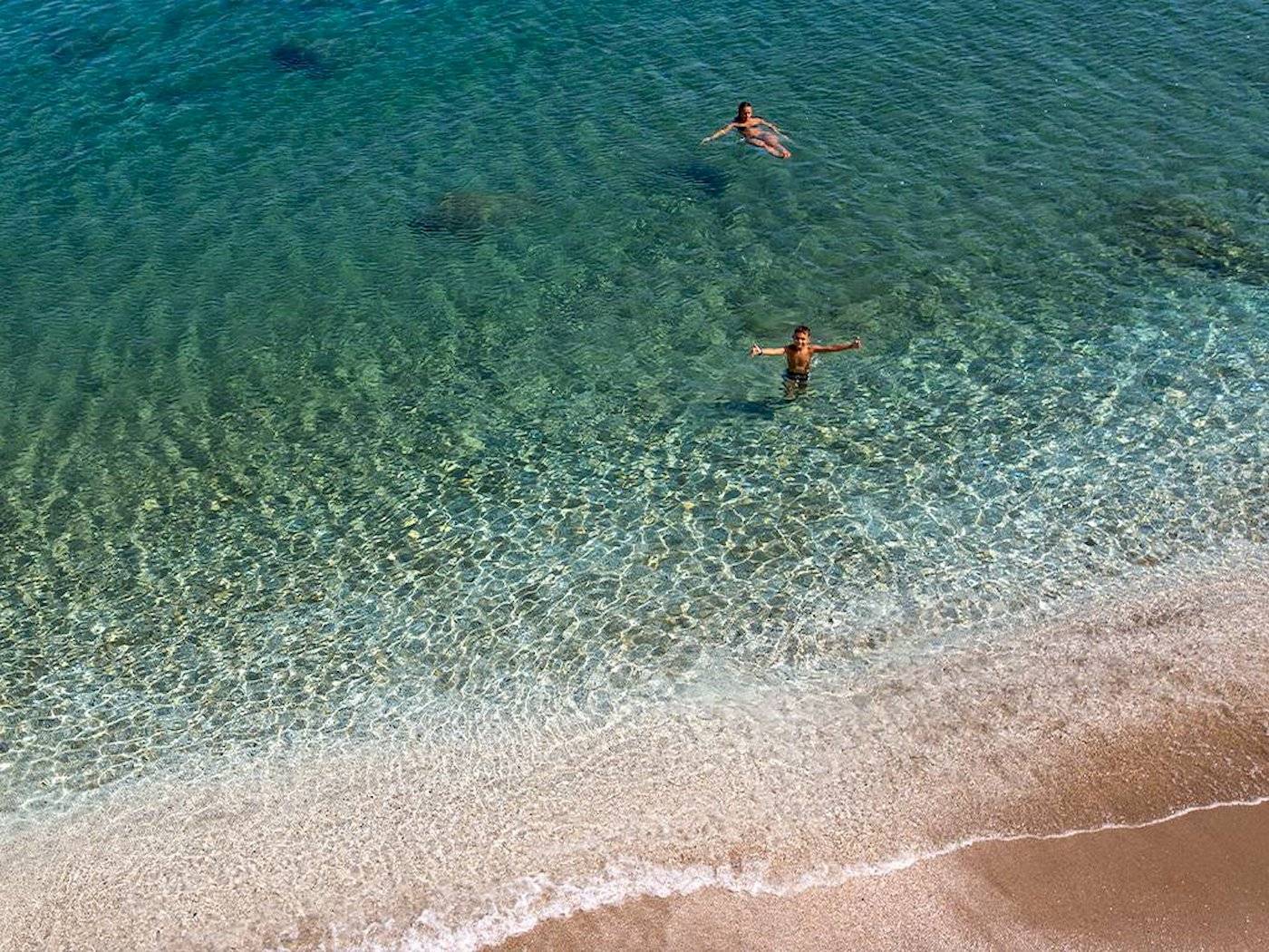 Zwei Personen schwimmen im kristallklaren Wasser von Chrissi Amoudia.
