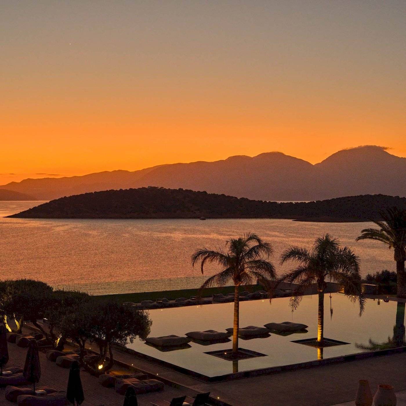 Abendlicher Sonnenuntergang im Hotel Minos Palace Hotel & Suites mit Blick auf das Meer und die Berge.