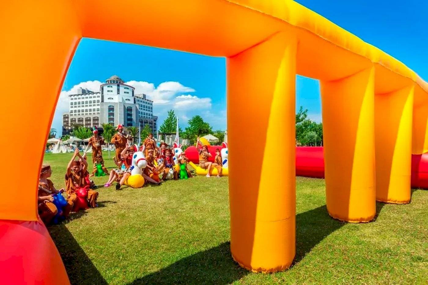 Kinder im Melas Lara Hotel spielen auf einer großen aufblasbaren Rutsche im Freien.