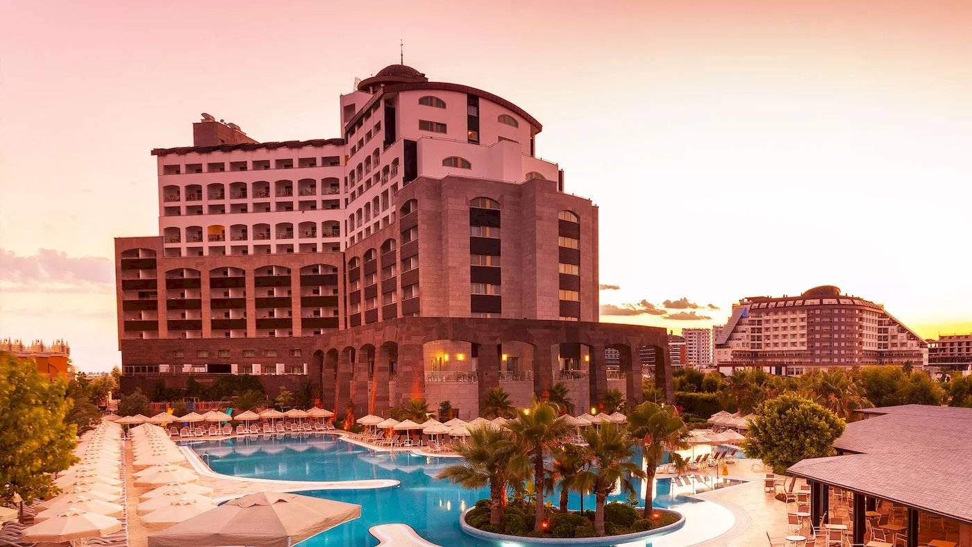 Melas Lara Hotel mit Swimmingpool und Palmen bei Sonnenuntergang