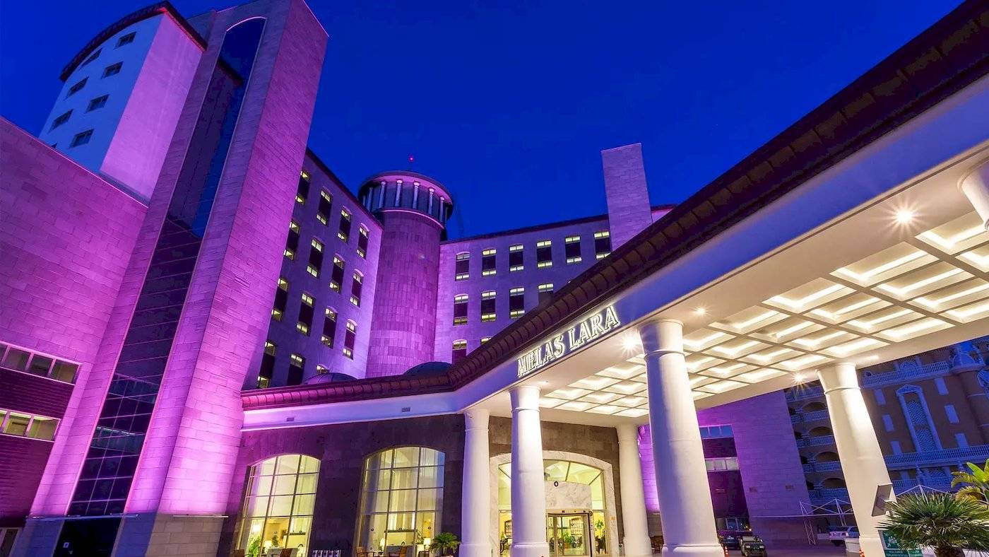 Melas Lara Hotel nachts mit lila Beleuchtung und hellem Eingangsbereich.