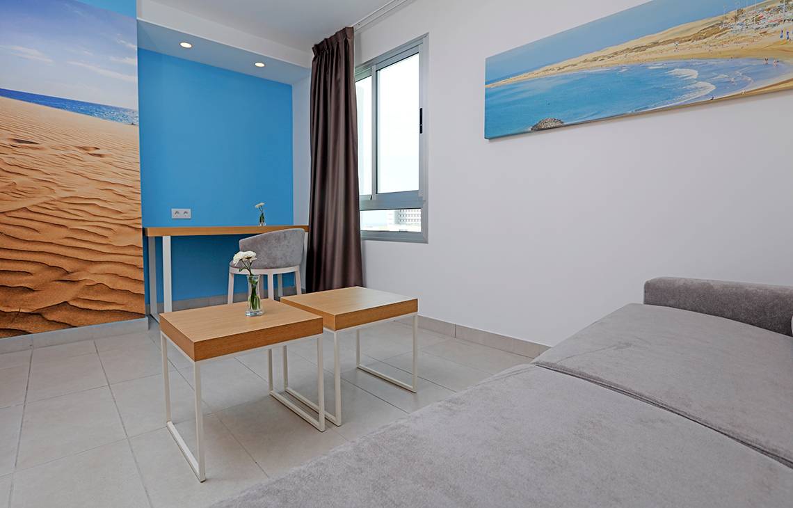 Hotelzimmer des LABRANDA Bronze Playa mit beigem Sofa, zwei Beistelltischen und Wanddekoration