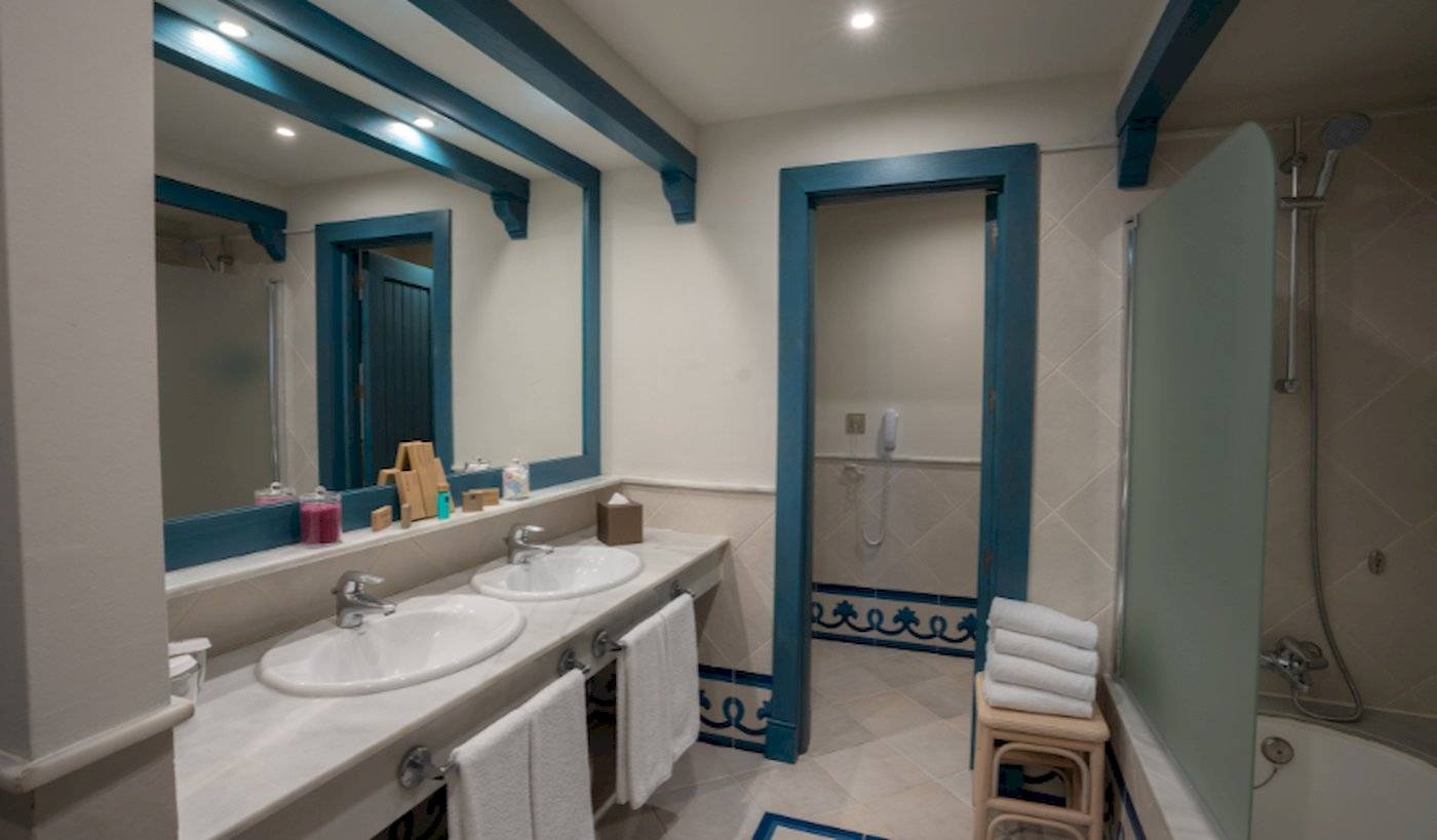 Badezimmer im LIVVO Volcan Lanzarote Hotel mit zwei Waschbecken, Spiegel, Badewanne und Dusche.