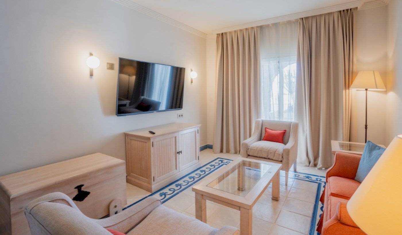 Wohnzimmer im LIVVO Volcan Lanzarote Hotel mit Fernseher, Couch und Tisch.