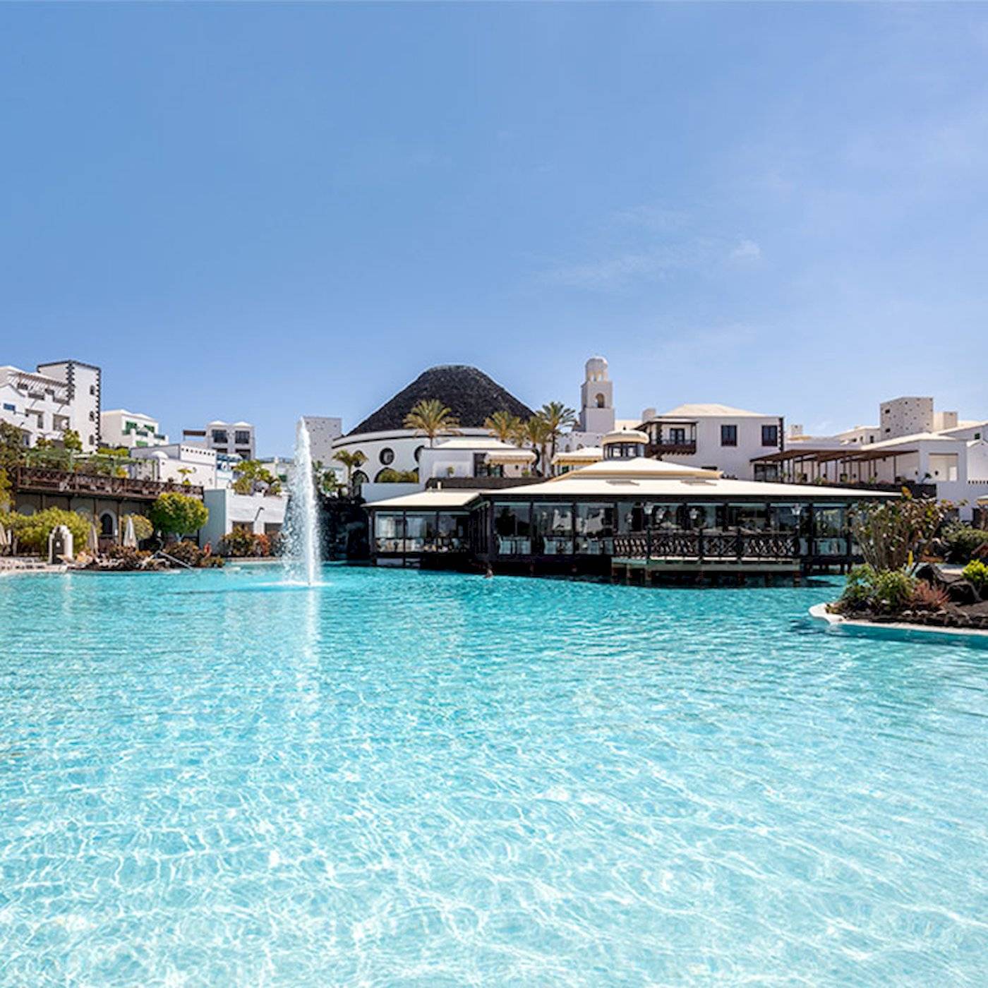 Außenpool des LIVVO Volcan Lanzarote Hotels mit weißen Gebäuden im Hintergrund.