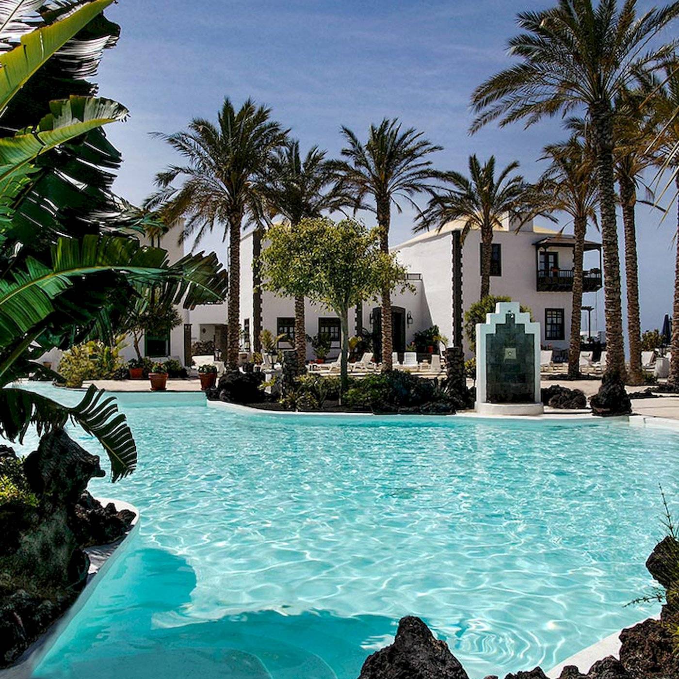 Außenpoolbereich des LIVVO Volcan Lanzarote Hotels mit Palmen und weißen Gebäuden