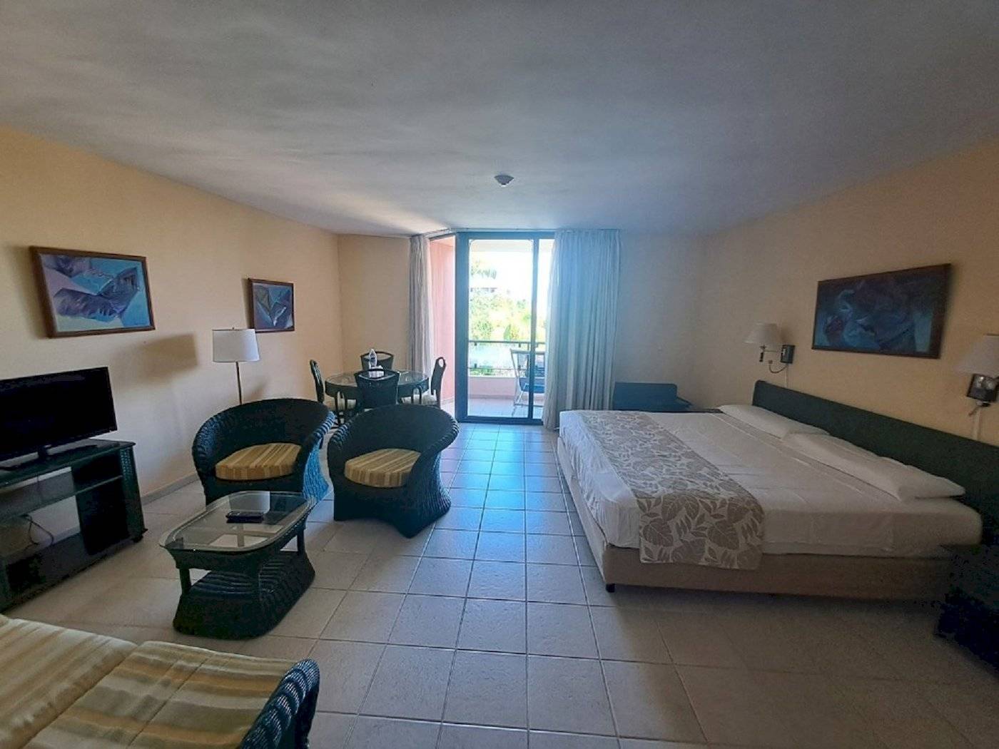 Zimmer im Muthu Playa Varadero Hotel mit Bett, Tisch, Stühlen und Fernseher.