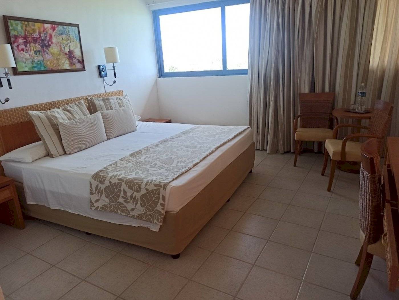 Hotelzimmer im Muthu Playa Varadero mit Bett, Fenster, Gemälde und Möbeln.