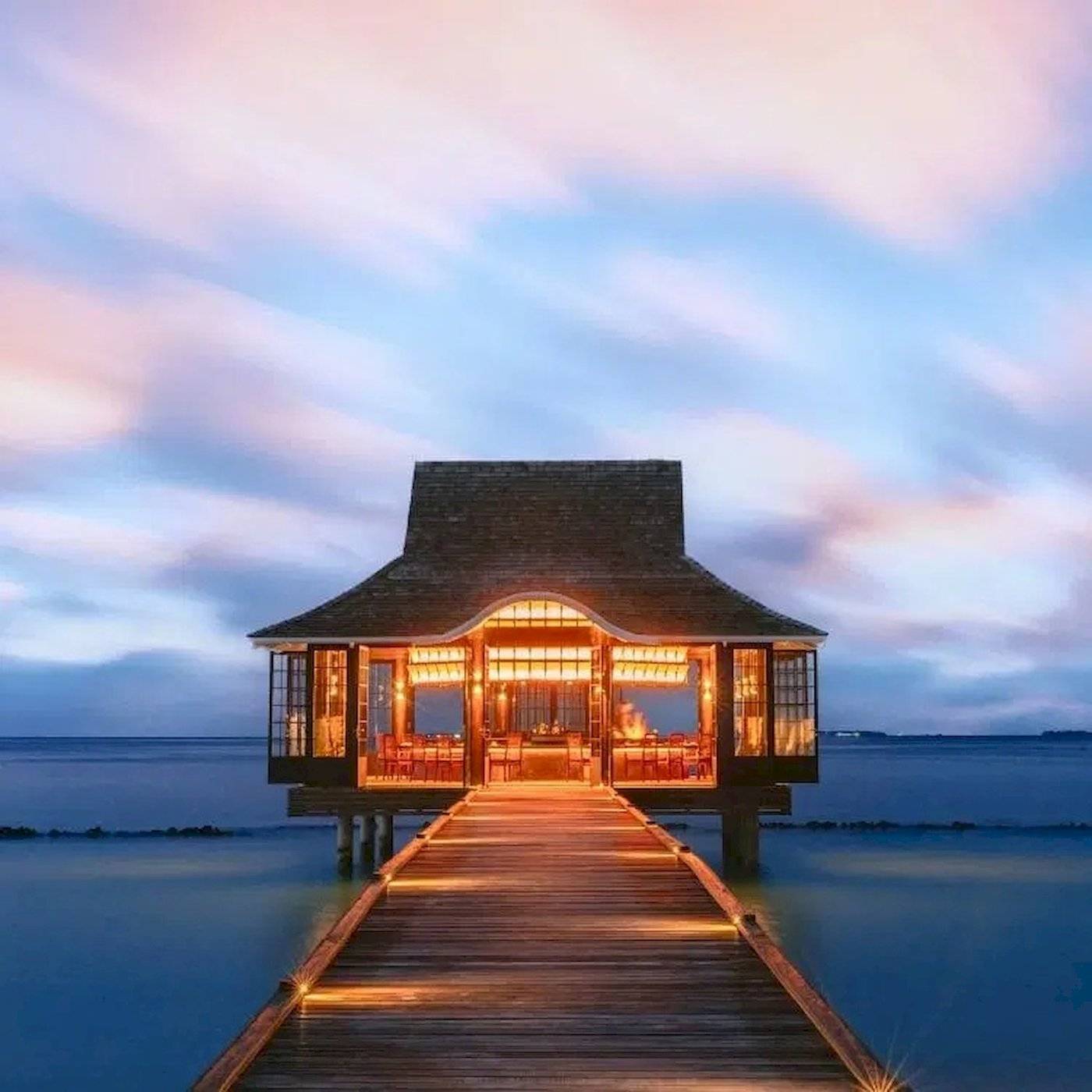 Nova Maldives Resort bei Nacht mit beleuchtetem Steg und illuminiertem Eingang