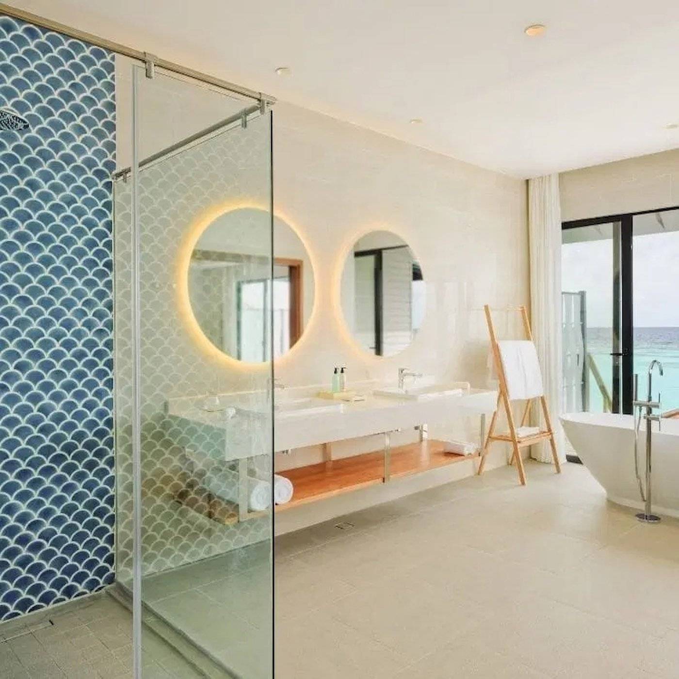 Badezimmer im Nova Maldives Hotel mit doppeltem Waschbecken und Badewanne mit Meerblick.