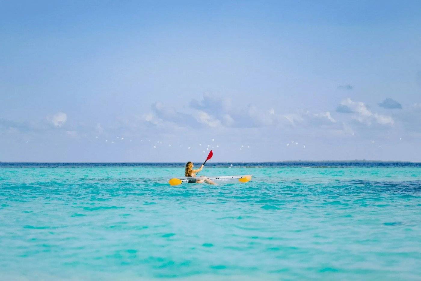 Eine Frau paddelt auf dem Ozean vor dem Nova Maldives.