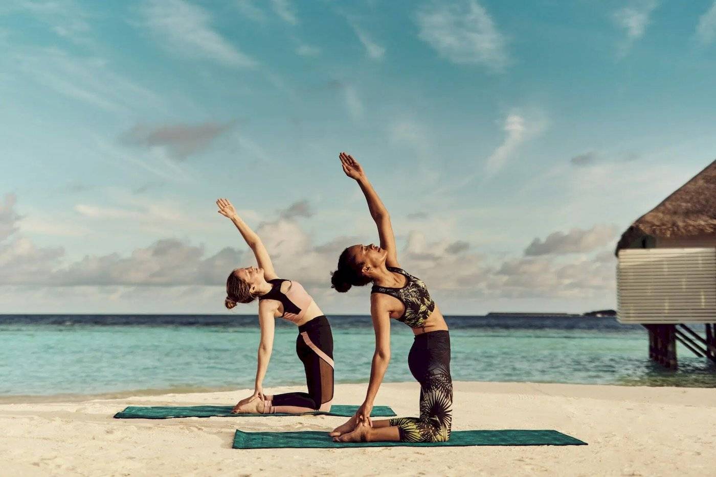Zwei Frauen machen Yoga auf dem Strand im Nova Maldives.