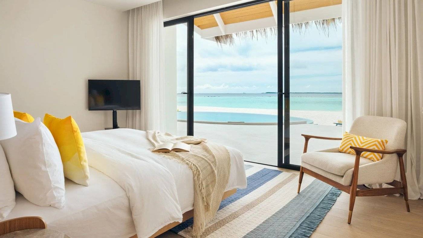 Schlafzimmer im Nova Maldives Hotel mit Meerblick, einem großen Bett und einem Fernseher.