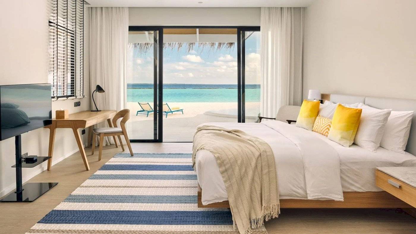 Hotelzimmer im Nova Maldives mit Meerblick, Bett, Schreibtisch und Fernseher.