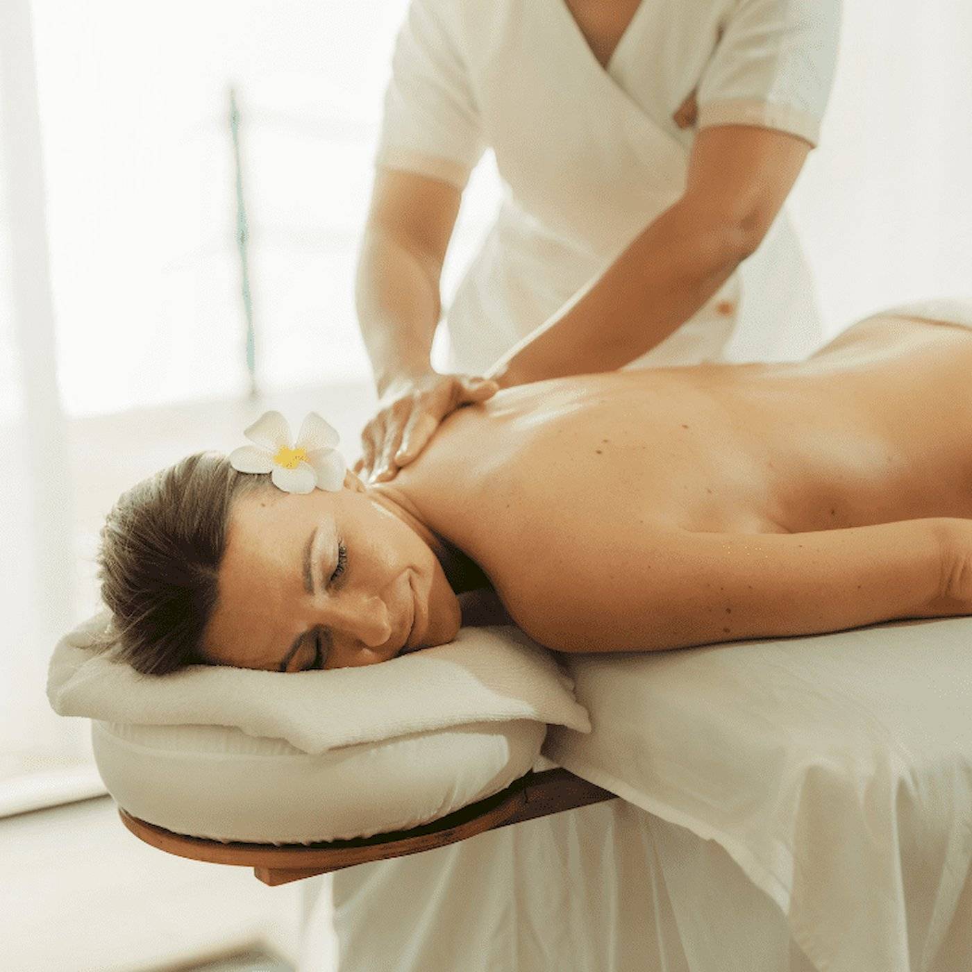 Massage-Behandlung im Nova Maldives Hotel, eine Frau genießt eine Rückenmassage.