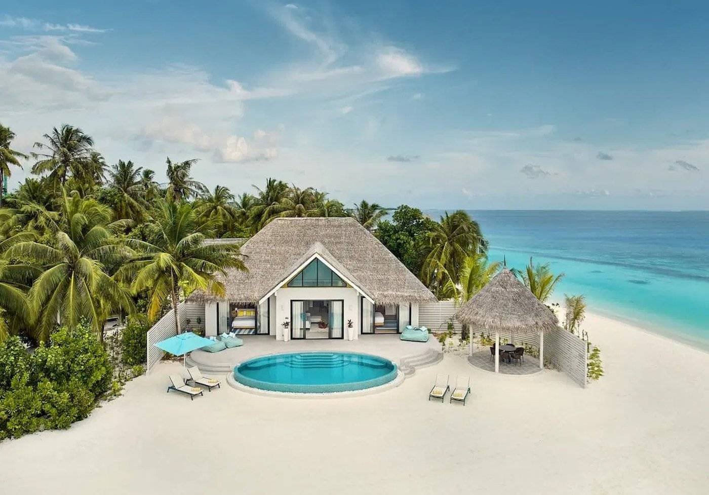 Luftaufnahme der Nova Maldives Villa mit Pool und Sonnenliegen auf dem Strand.
