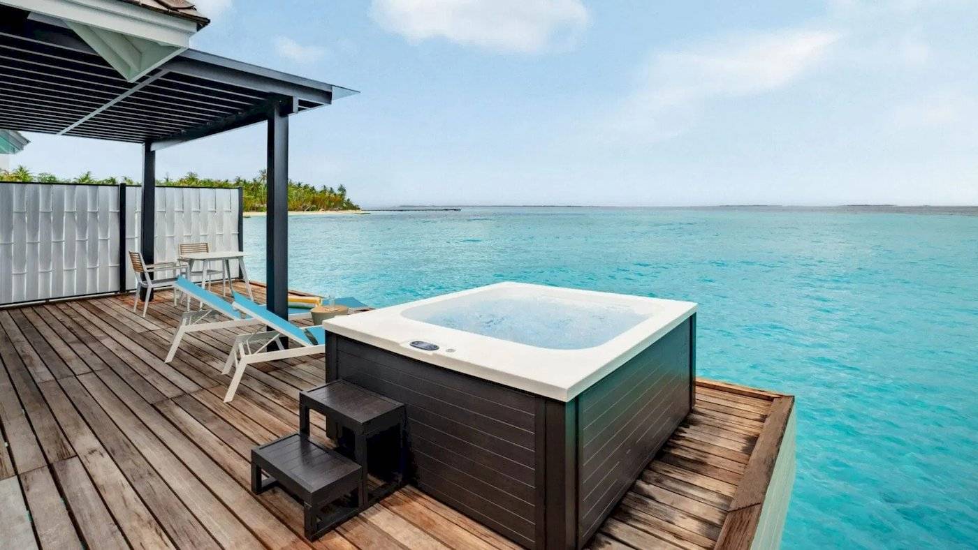 Ein Whirlpool auf einer Holzterrasse mit Blick auf das Meer im Nova Maldives Hotel.