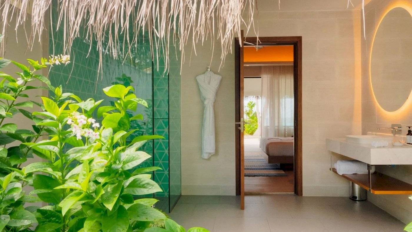 Außenbereich des Badezimmers im Nova Maldives mit grüner Wand und Dusche