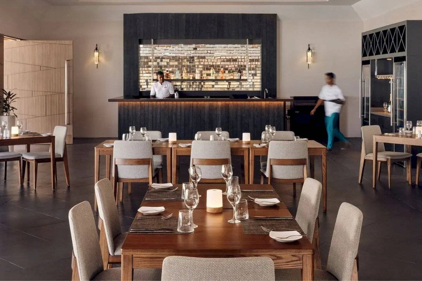 Restaurant-Innenbereich des Nova Maldives mit Tischen, Stühlen und Bar.