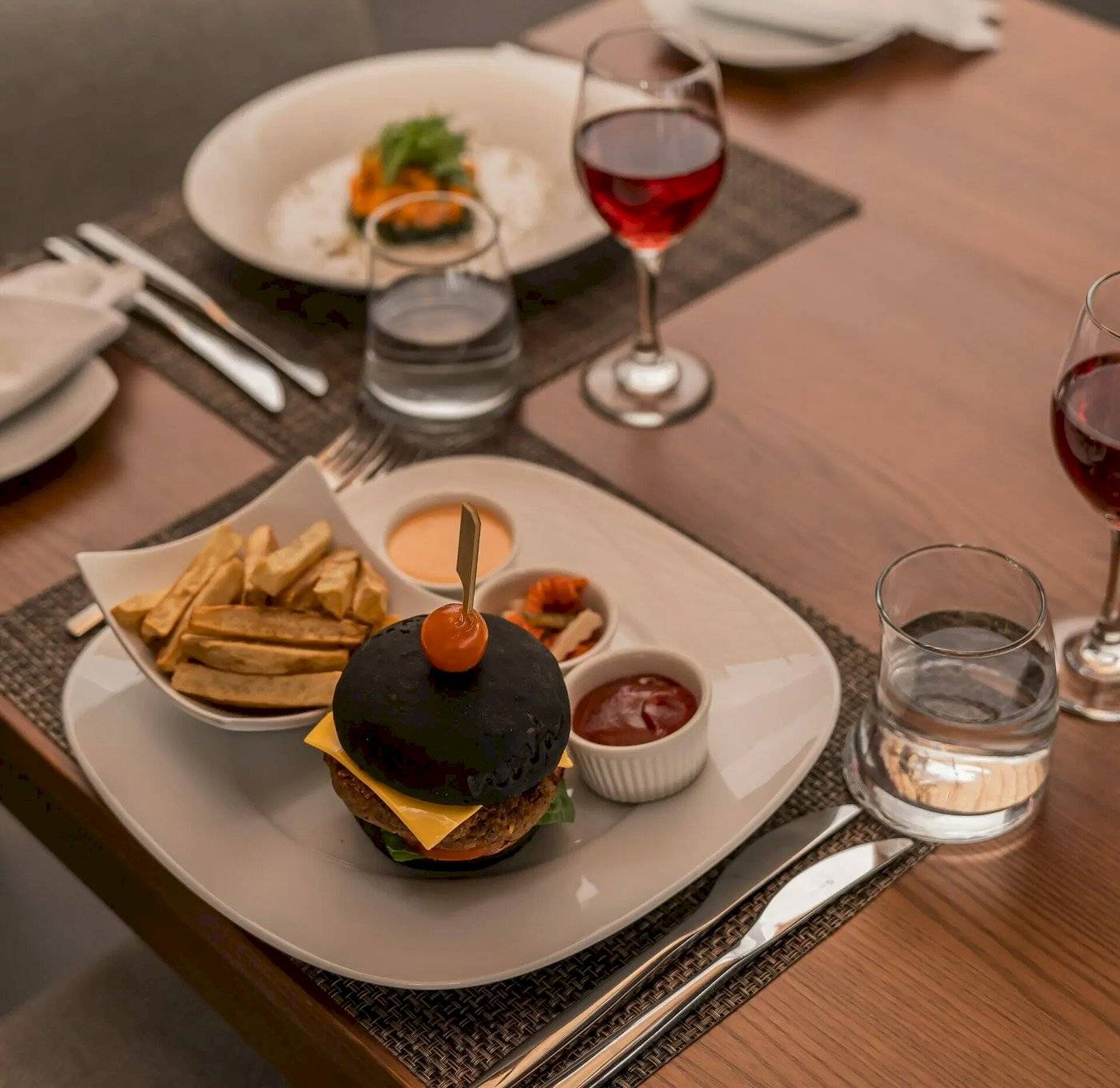 Nova Maldives Hotel Essen auf Tisch mit Burger, Pommes, Glas Wasser und Wein