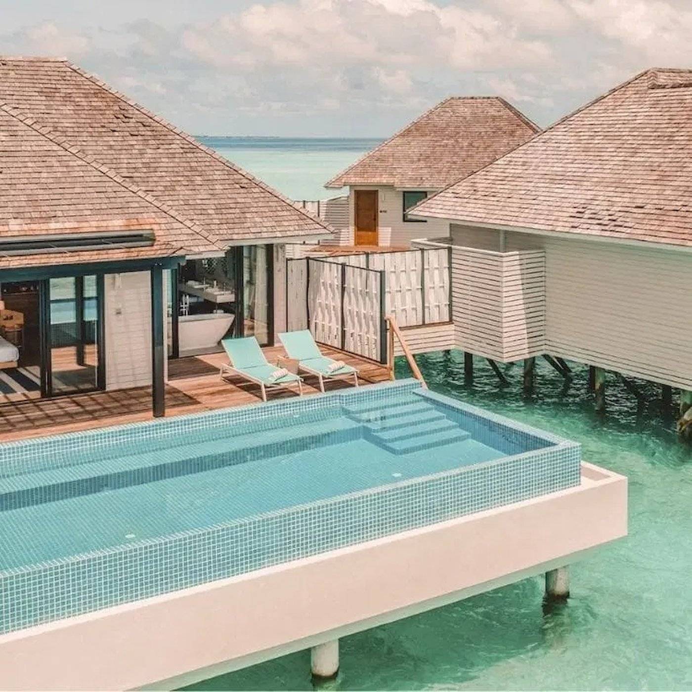 Nova Maldives Hotel Pool-Villa mit zwei Liegen und Badewanne am Meer.