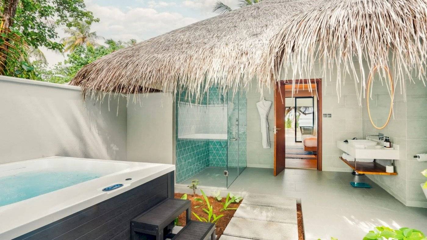 Ein Freiluft-Badezimmer mit Badewanne, Dusche und Waschbecken im Nova Maldives Hotel.