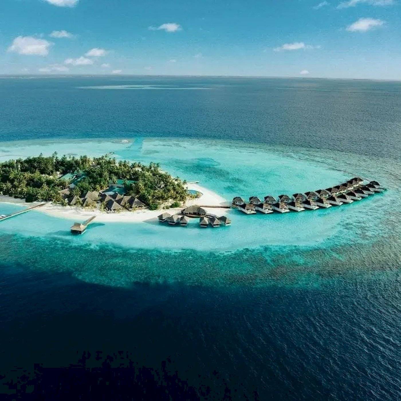 Luftaufnahme der Nova Maldives Insel mit Wasservillen und blauem Ozean.