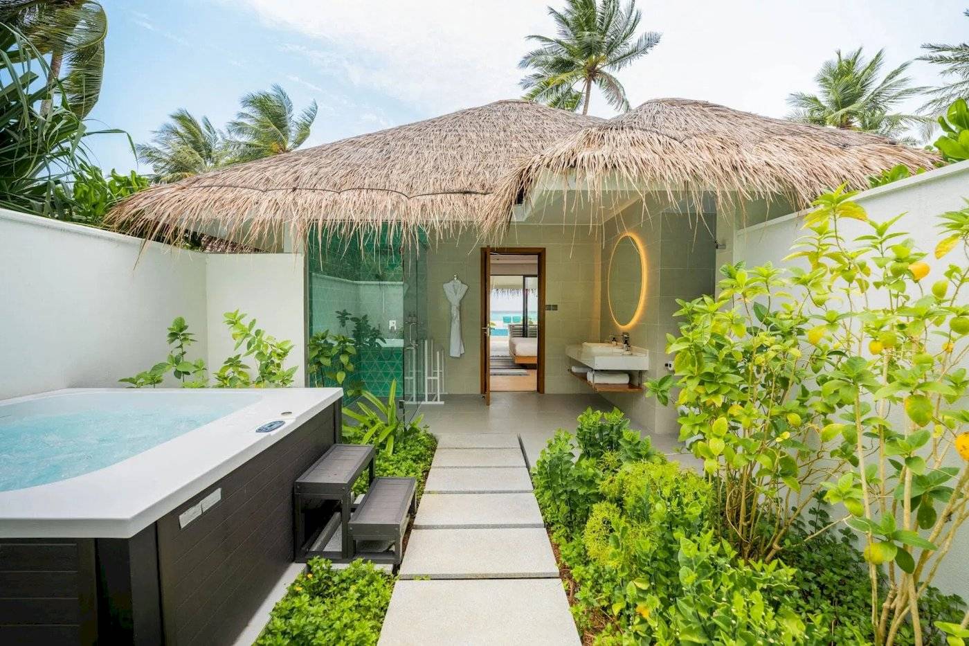 Außenbereich des Nova Maldives Hotels mit einer kleinen Hütte und einem Jacuzzi