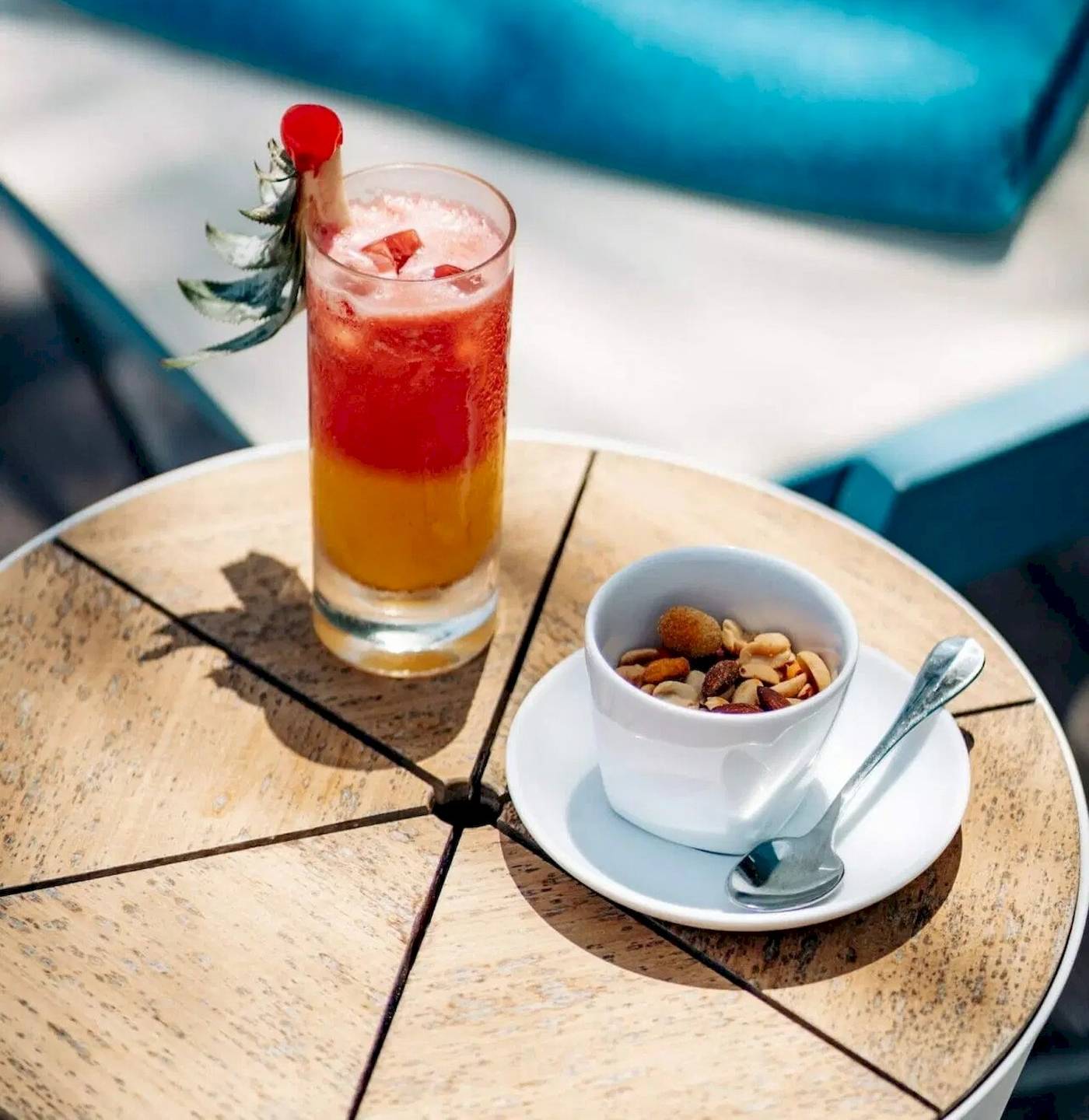Cocktail auf einem Tisch im Nova Maldives Hotel mit einer Sonnenbrille und einem Hut im Hintergrund.