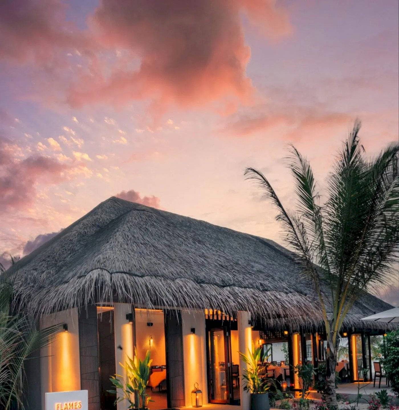 Außenansicht der Nova Maldives Grill House bei Sonnenuntergang mit beleuchteten Eingängen.