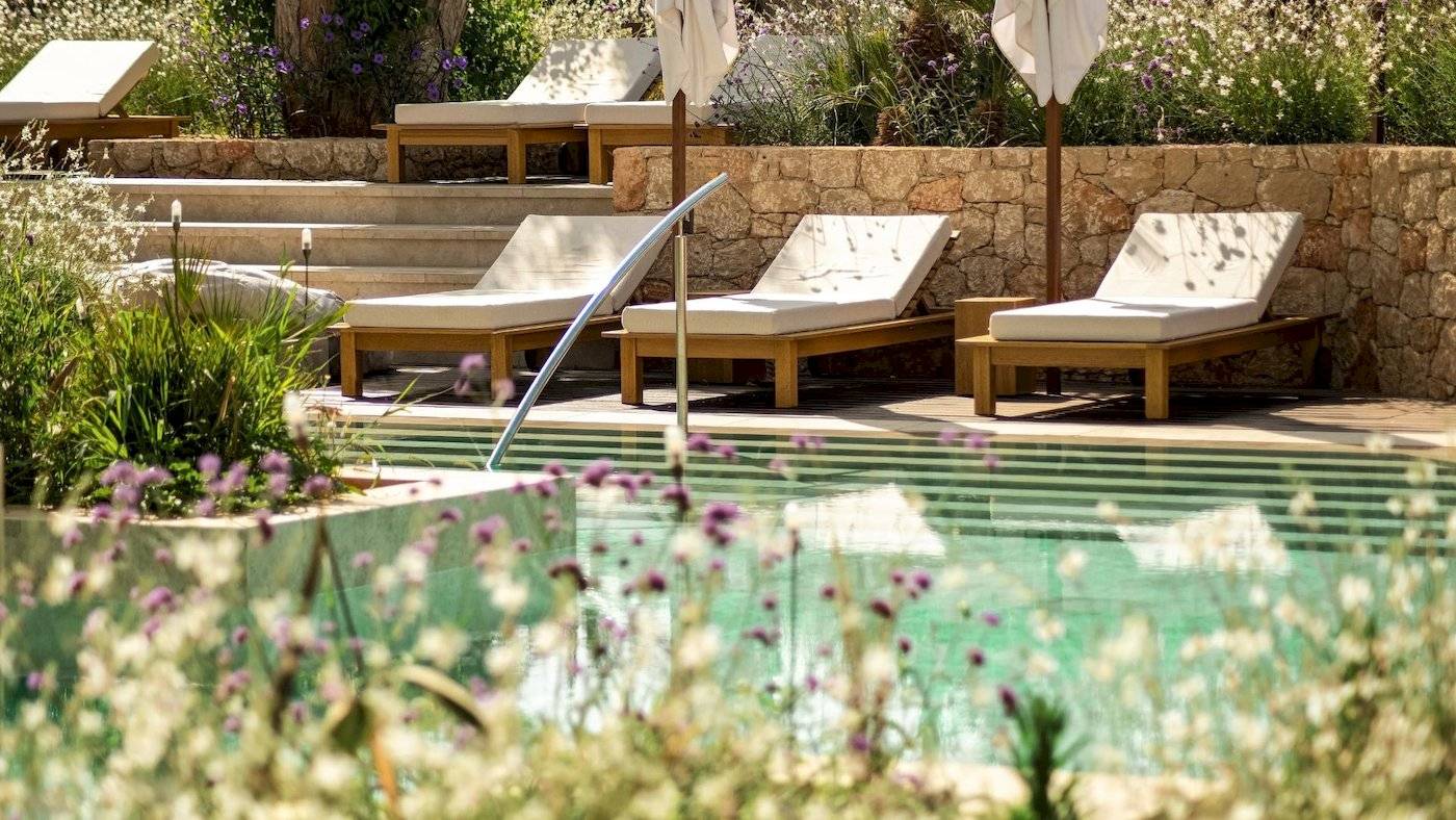 Pool-Lounge mit Sonnenliegen und Blumen am Mitsis Selection Rinela Hotel