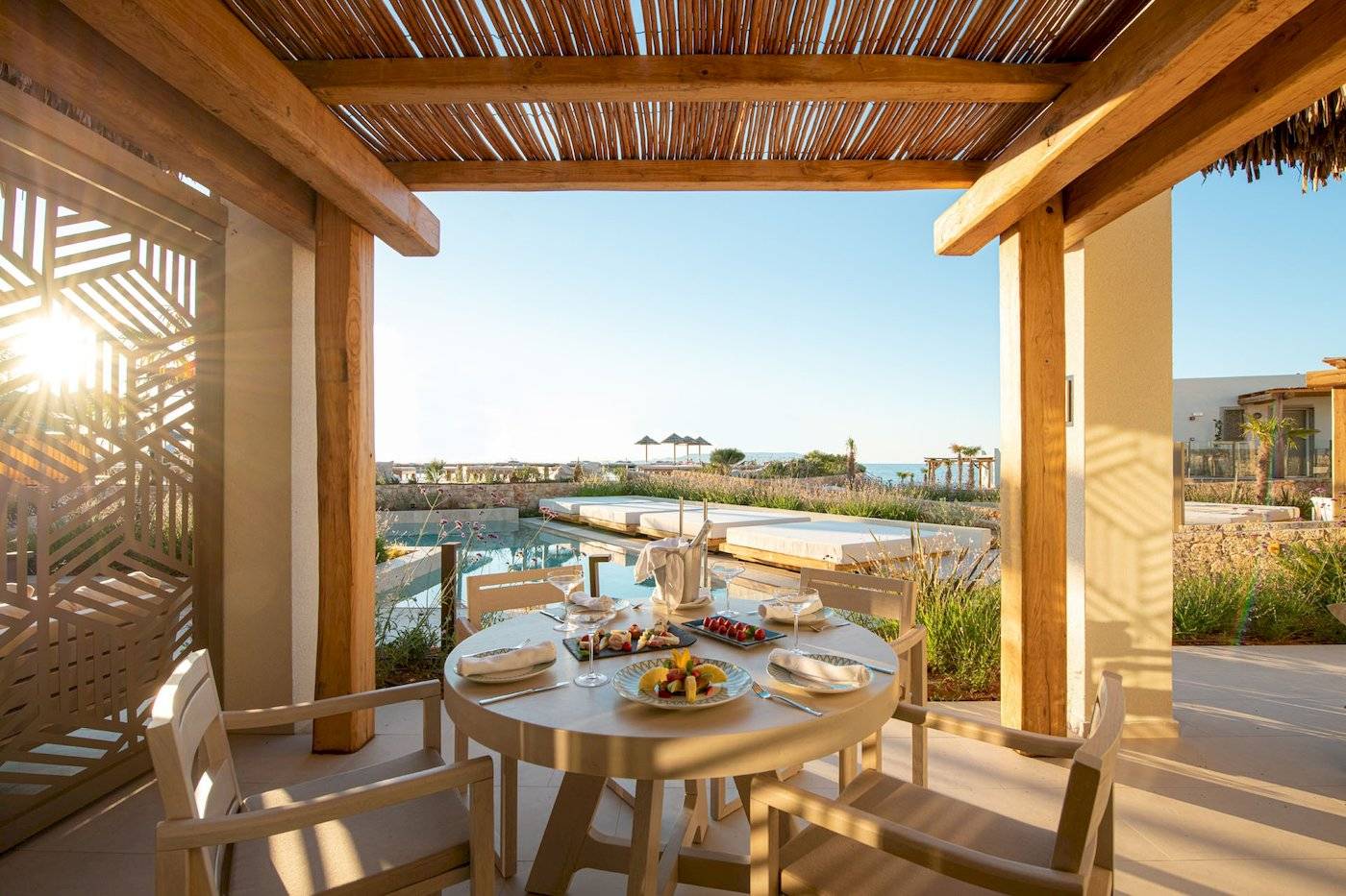 Terrasse im Mitsis Selection Rinela Hotel mit Aussicht auf den Pool und das Meer.