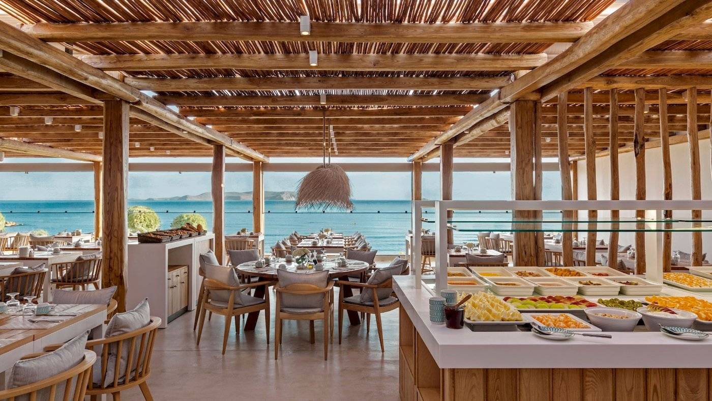 Innenansicht des Restaurants im Mitsis Selection Rinela Hotel mit Blick auf das Meer.