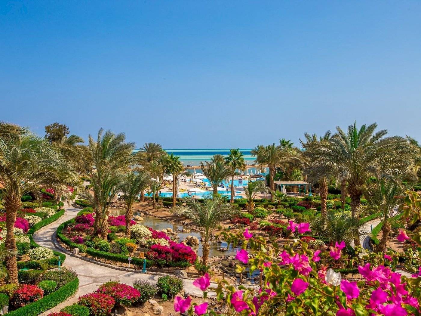 Außenbereich des Mövenpick Resort & Spa El Gouna mit Palmen, Blumen und Blick auf das Meer