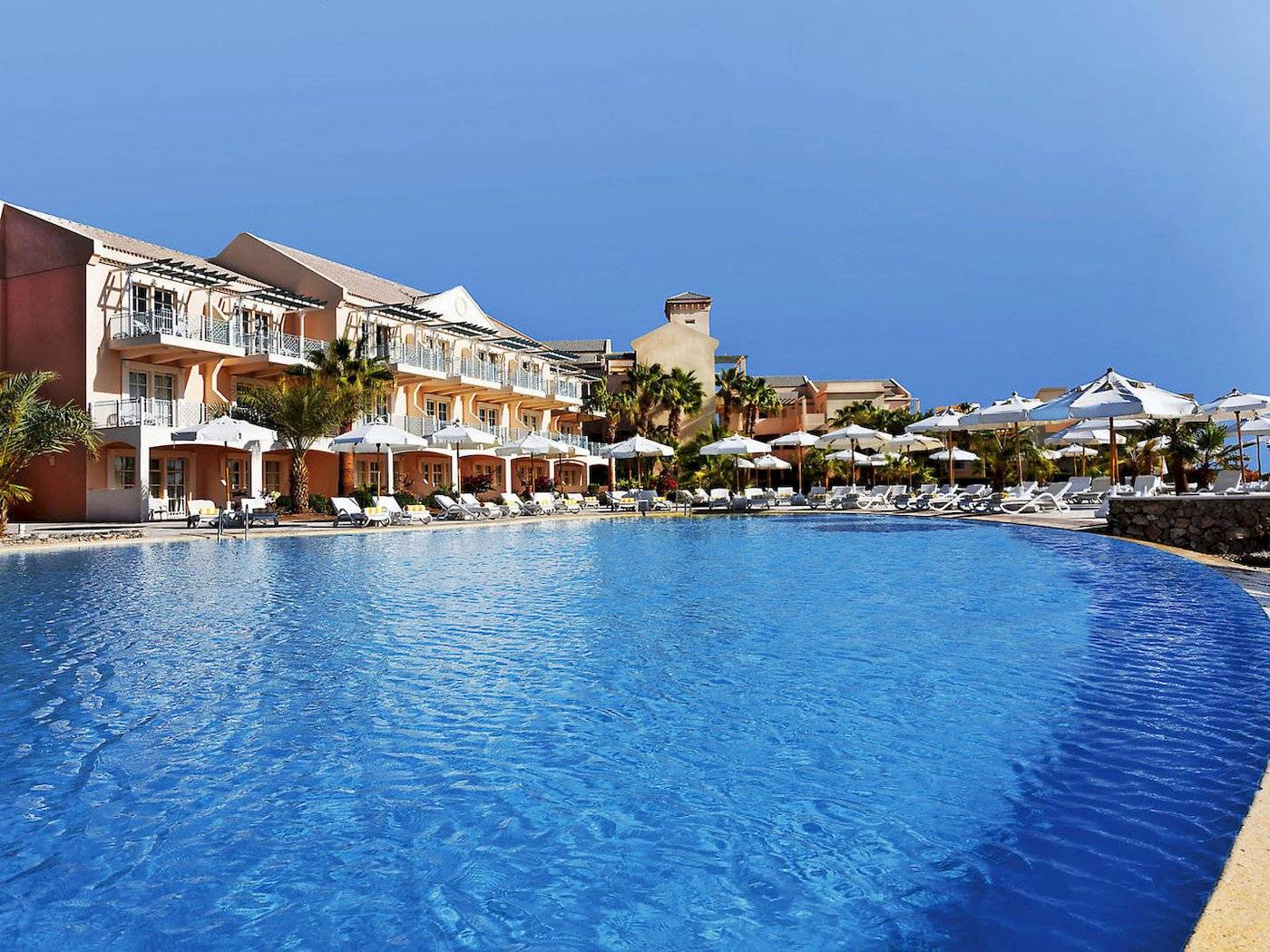 Poolbereich im Moevenpick Resort & Spa El Gouna mit vielen Sonnenliegen und umliegenden Hotels
