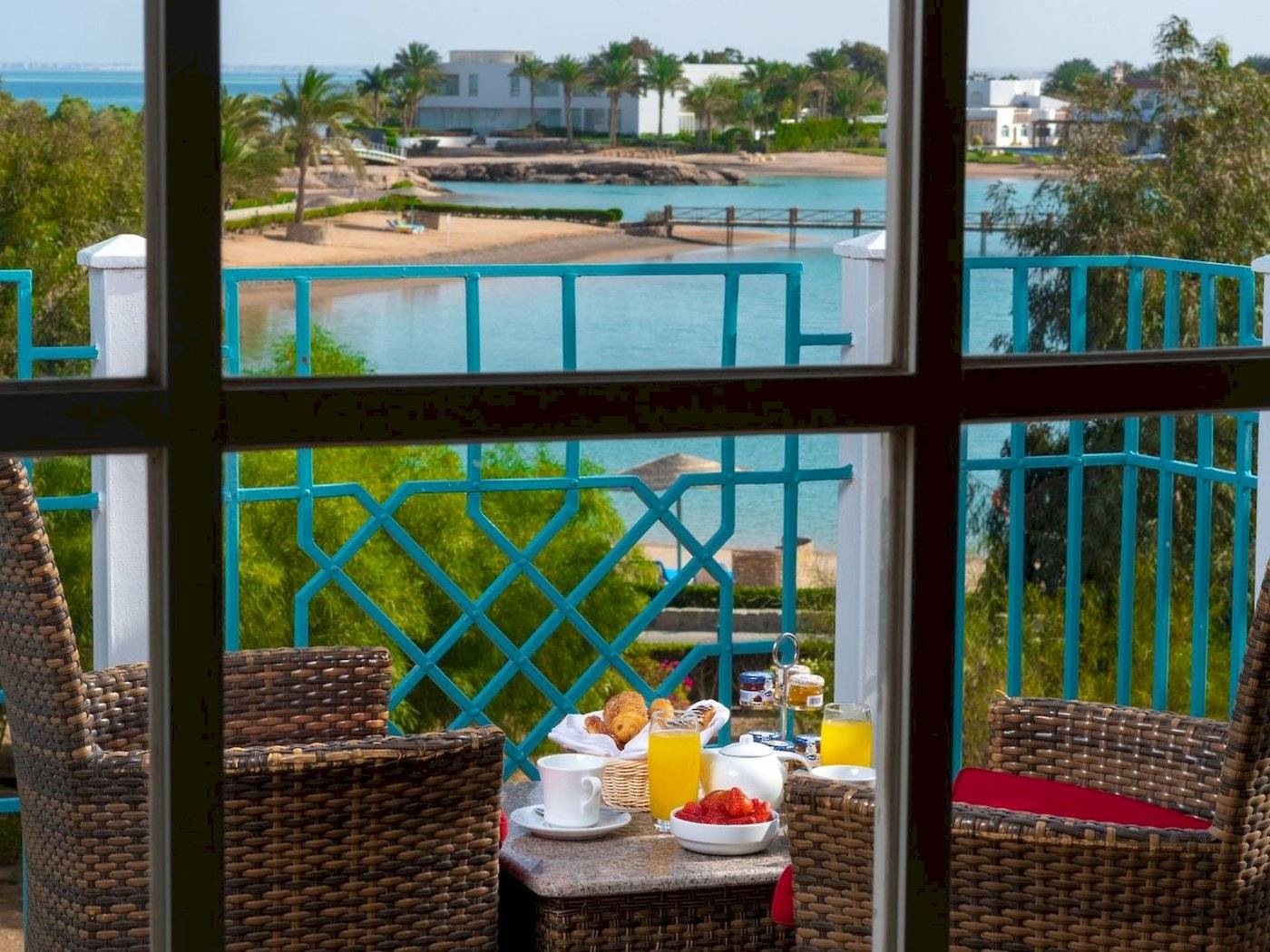 Frühstück auf dem Balkon im Mövenpick Resort & Spa El Gouna mit Blick auf den Ozean und eine tropische Landschaft.
